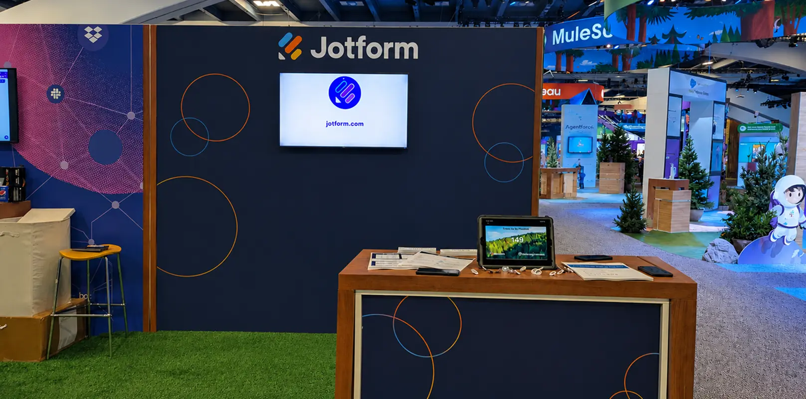 The Jotform booth at Dreamforce 2023, with a tablet on the demo counter showing the running count of trees to be planted